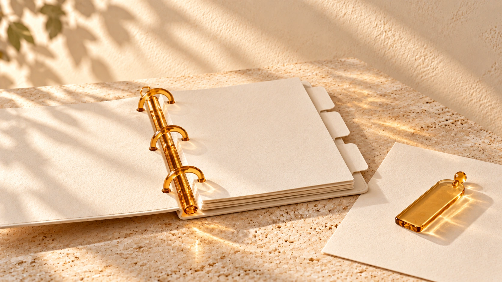 An open ivory binder with amber-glass rings sits beside a loose page and amber bookmark.